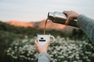 person pouring water from white ceramic mug